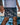 Gray geometric-print Gracie Barra shorts with the white stacked wordmark on the leg, worn with a light gray tee by the shore