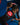 Black Gracie Barra rashguard with the red Barra Shield back patch and white Equipe print, worn with black spats on a blue mat.