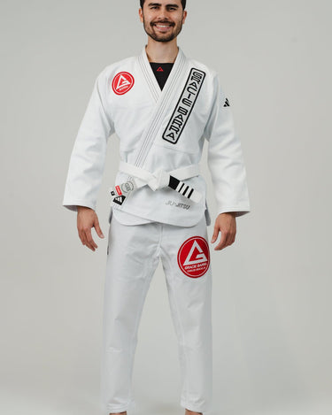 Front view of man wearing Pro Lite Comp Men’s Kimono by adidas in white with black and red Gracie Barra branding, barefoot on light gray background