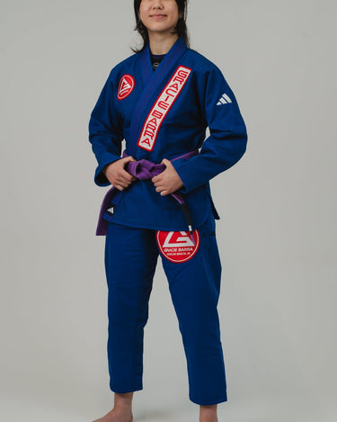 Woman wearing a blue Pro Lite Comp Kimono by adidas with Gracie Barra branding, standing in a confident pose against a plain background.