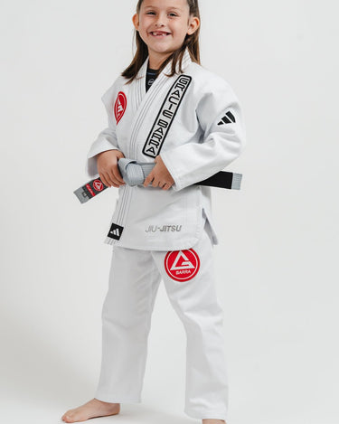 Child wearing the left side of a white Pro Lite Comp Youth Kimono by adidas with Gracie Barra branding on a white background