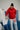 Gracie Barra Professor wearing the 40 Years Competition Team red zip hoodie while teaching inside a Gracie Barra jiu-jitsu school, highlighting the unisex fit and Red Shield chest logo