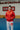 Gracie Barra Professor wearing the 40 Years Competition Team red zip hoodie inside a Gracie Barra jiu-jitsu school, showing the Red Shield chest logo and unisex fit in a training environment
