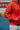 Close-up of the 40 Years Competition Team red zip hoodie worn in a Gracie Barra jiu-jitsu school, highlighting the raised COMPETITION TEAM sleeve detail and premium midweight fleece construction