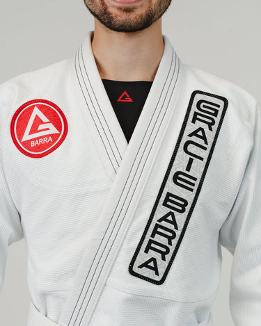 Close-up of upper torso wearing Pro Lite Comp Men’s Kimono by adidas in white featuring embroidered Gracie Barra patches on shoulder and lapel