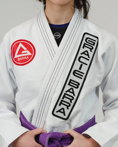 Close-up of the adidas Pro Lite Comp Kimono in white with Gracie Barra branding on the chest and lapel, showcasing fabric texture and embroidery detail.