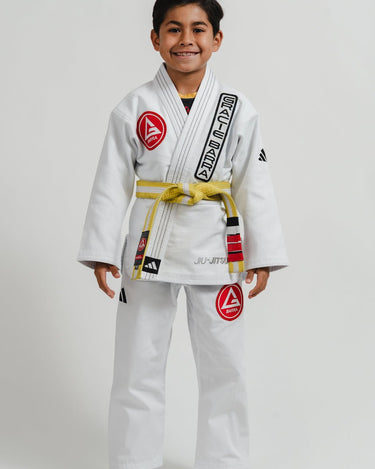 Child wearing a white Pro Lite Comp Youth Kimono by adidas with Gracie Barra branding on a white background