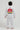 Child wearing a white Pro Lite Comp Youth Kimono by adidas with Gracie Barra and Equipe branding on the back, against a white background