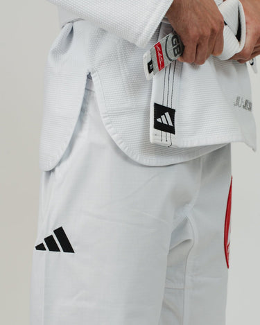 Close-up of right hip and waist area on Pro Lite Comp Men’s Kimono by adidas in white showing adidas branding, Jiu-Jitsu embroidery, and athlete gripping belt
