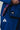 Close-up of a woman wearing a blue Pro Lite Comp Kimono by adidas, highlighting the white adidas logos on the jacket and pants, with red contrast stitching on the lapel, against a neutral background.