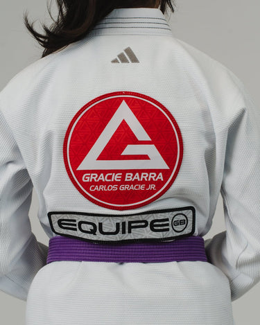 Close-up of the back of a white Pro Lite Comp Kimono by adidas, featuring large Gracie Barra and Equipe GB patches on a plain background.