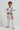 Child wearing a white Pro Lite Comp Youth Kimono by adidas with Gracie Barra and Jiu-Jitsu logos, viewed from the left on a plain background