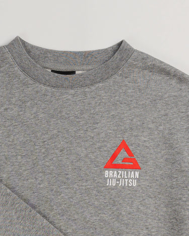 Close-up of grey Arte Suave V2 kids crewneck sweatshirt by Gracie Barra, featuring Legacy G chest logo with “Brazilian Jiu-Jitsu” text in white.