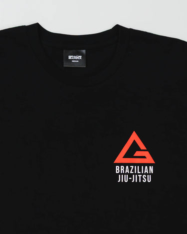 Close-up of the black Arte Suave V2 kids’ T-shirt by Gracie Barra, showcasing the red and white Legacy G chest logo with “Brazilian Jiu-Jitsu” text, displayed on a light gray background