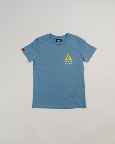 Full view of the Arte Suave V2 kids’ T-shirt in blue by Gracie Barra, featuring a small yellow Legacy G logo above “Brazilian Jiu-Jitsu” text on the left chest, and a red sleeve tag, displayed on a light gray background.