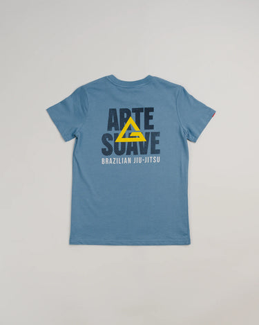 Back view of the Arte Suave V2 kids’ T-shirt in blue by Gracie Barra, featuring large black “Arte Suave” text with a yellow Legacy G logo overlay and “Brazilian Jiu-Jitsu” in white beneath, displayed on a light gray background.