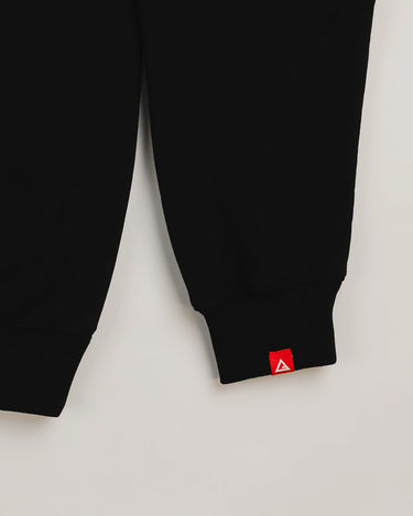 Close-up of black Arte Suave V2 men’s French terry crewneck sleeve by Gracie Barra, featuring a red woven tag with the white Legacy G logo above the ribbed cuff.