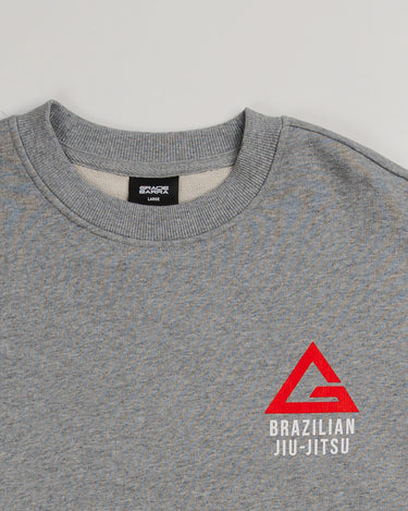 Close-up of grey Arte Suave V2 men’s crewneck sweatshirt in French terry by Gracie Barra, featuring red Legacy G chest logo with “Brazilian Jiu-Jitsu” text in white.