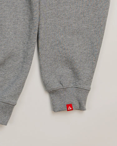 Sleeve detail of grey Arte Suave V2 men’s crewneck sweatshirt in French terry by Gracie Barra, featuring red woven tag with Legacy G logo near ribbed cuff.