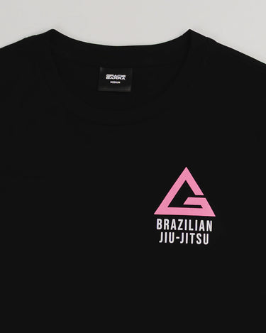 Close-up of the Arte Suave V2 women’s black T-shirt by Gracie Barra, showcasing a pink Legacy G logo above “Brazilian Jiu-Jitsu” text on the left chest, displayed on a light gray background.