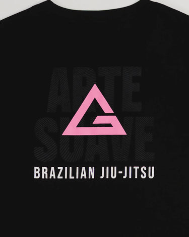 Close-up of the Arte Suave V2 women’s black T-shirt back, showcasing a pink Legacy G logo above “BRAZILIAN JIU-JITSU” text with faint “ARTE SUAVE” lettering in the background, displayed on a light gray backdrop.