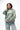 Arte Suave V3 Womens Hoodie in sage, three-quarter front on model. Relaxed oversized fit, black Legacy G logo and white 'Arte Suave' chest script.