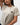 Arte Suave V3 Womens Tee in natural, three-quarter front close-up showing the chest print: black Legacy G logo above white 'Arte Suave' script.