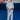 Gracie Barra professor standing on blue mats wearing the white AXIS Kimono by adidas with black belt inside a Gracie Barra school.