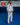 Gracie Barra professor standing on blue mats wearing the white AXIS Kimono by adidas with black belt inside a Gracie Barra school.