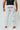 Athlete modeling white Atleta competition gi pants from behind, showing the red Gracie Barra print on the back waist and straight-leg competition cut