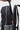 Hand sliding a laptop into the padded laptop sleeve of the black Barra Beachwalk Backpack, with a red Gracie Barra zipper pull and gray mesh side pocket.