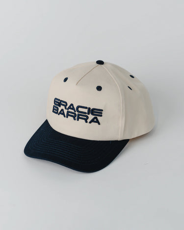 Angled front view of Barra Cap in natural color with contrasting navy brim and raised embroidery reading “Gracie Barra” across the crown.