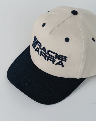 Angled close-up of Barra Cap in natural with navy brim and raised navy “Gracie Barra” embroidery across the front panels.
