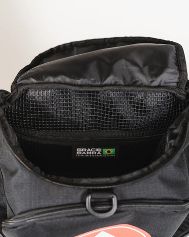 Interior view of Black Barra da Tijuca Backpack showing mesh storage pocket and woven label with Gracie Barra logo and Brazilian flag detail.