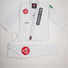 Full front view of the Barra da Tijuca White Kimono, showing the jacket with Red Shield patch, Gracie Barra lapel patch, EQUIPE embroidery, Brazilian flag shoulder patch, and matching pants with the Red Shield patch laid below.