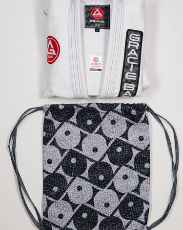 Folded Barra da Tijuca White Kimono jacket with visible Red Shield and Gracie Barra patches, displayed above the patterned drawstring bag inspired by Barra da Tijuca sidewalk mosaics.