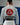 Back view of a Gracie Barra professor wearing the Barra da Tijuca White Kimono, showcasing the large red Gracie Barra back patch and EQUIPE patch while standing on the academy mats.