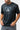 Front of the black Barra da Tijuca Terra Mar tee held at the hem, showing the gray boardwalk-tile square print, Legacy G and BARRA DA TIJUCA text.