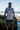 Gray Gracie Barra Barra da Tijuca Terra Mar tee worn on a rocky beach, front view with the boardwalk-pattern square chest graphic.