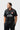 Student wearing the black Barra Origins jersey, front view with red-tipped collar, white piping, Barra Shield and BRAZILIAN JIU-JITSU chest print.