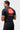 Three-quarter back view of the black Gracie Barra Close Contact Rashguard with the red Barra Shield and white Equipe print.