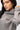 Emblem Womens Hoodie in Gray — close-up on model showing the tonal Gracie Barra chest emblem, hood, and dropped-shoulder sleeve.
