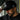 Man wearing black adidas snapback cap with Gracie Barra Legacy G logo and black Gracie Barra t-shirt, adjusting brim outdoors near building