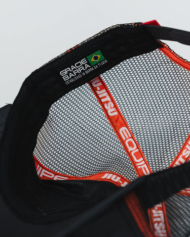 Interior view of the black Equipe Motion Cap showing breathable mesh lining, red Jiu-Jitsu and Equipe branded taping, and a Barra da Tijuca origin label stitched inside the sweatband, photographed flat on a white background.