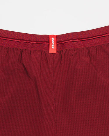 Close-up of the waistband on Equipe Motion Men’s Shorts in maroon, featuring a red Equipe tag and grid-pattern ventilation fabric.