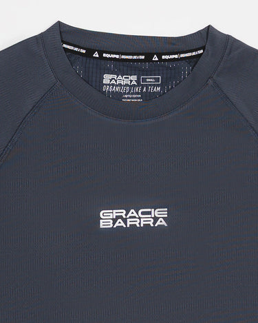 Close-up of grey Equipe Motion Men’s Tee with Gracie Barra stacked logo on chest and raglan stitching detail.