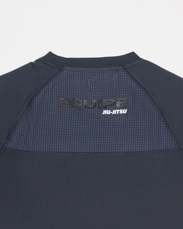 Close-up of grey Equipe Motion Men’s Tee showing breathable mesh back panel with reflective ‘Equipe Jiu-Jitsu’ print for visibility.