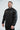 Black Equipe Warm Up Jacket worn at an angle, showing the gray EQUIPE sleeve print, zippered hand pocket and drop shoulder stitching.