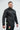 Black Gracie Barra Equipe Warm Up Jacket, side front view, with white Jiu-Jitsu print, Brazil flag patch and zippered sleeve pocket.