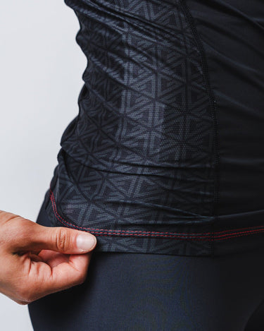 GB Essentials Women’s Rashguard in brown colorway, side panel close-up highlighting geometric pattern fabric, reinforced hem stitching, and flexible stretch fit.